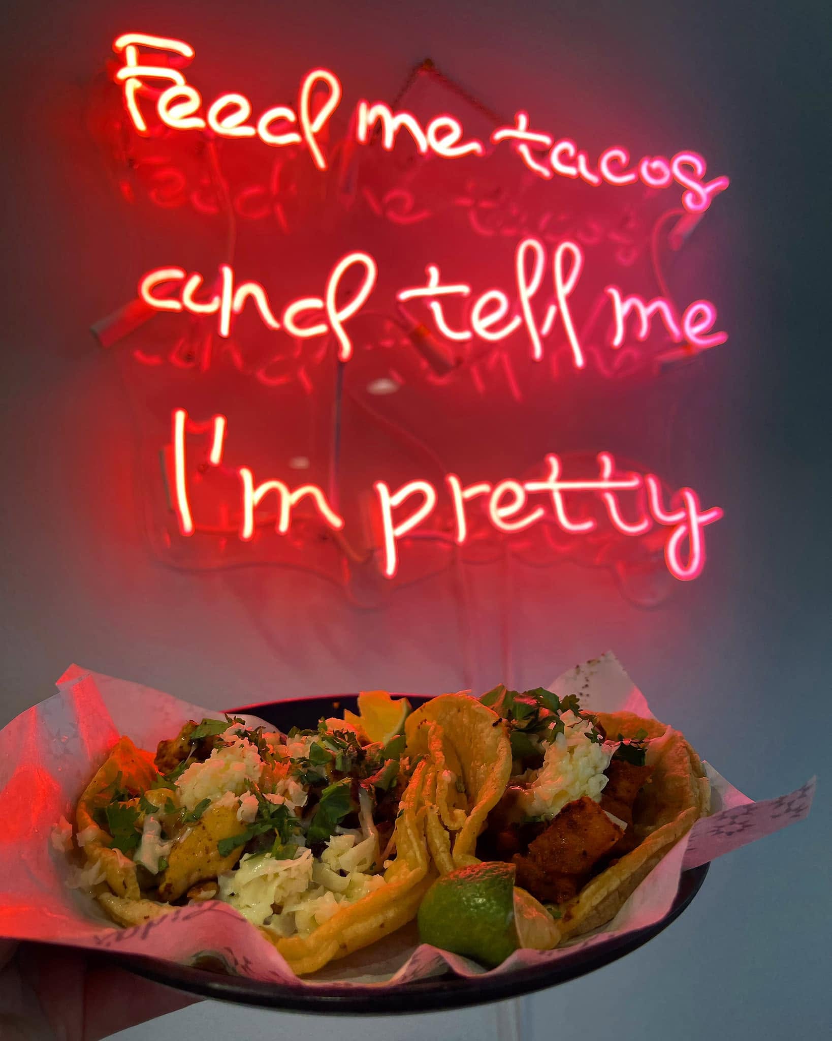 Tacos beneath the Frida's neon sign reading Feed Me Tacos and Tell Me I'm Pretty